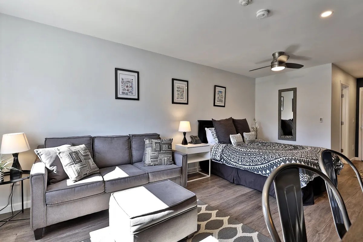 A cozy living area with a comfortable sofa, bed in the background, soft lighting, and framed artwork. The atmosphere is welcoming and perfect for winding down after an exciting evening out.