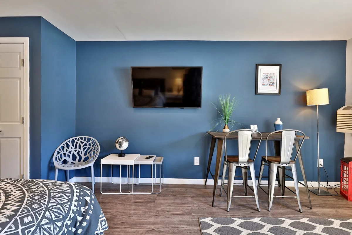 The image features a cozy dining nook with a small table and two chairs, set against a blue accent wall and complemented by a decorative globe and lamp. The setup is intimate, ideal for sharing meals or working, and evokes the flexible dining experience described in the section. The arrangement suggests both functionality and comfort, suitable for a variety of meal moments.