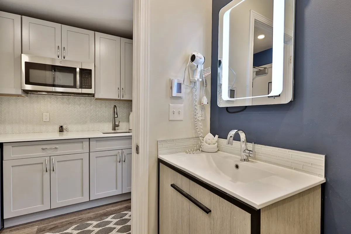 A stylish and functional kitchen space featuring modern cabinets, a contemporary sink, and an elegant mirror. The setting hints at both the preparation for a social evening out and the comfort of returning home afterwards.